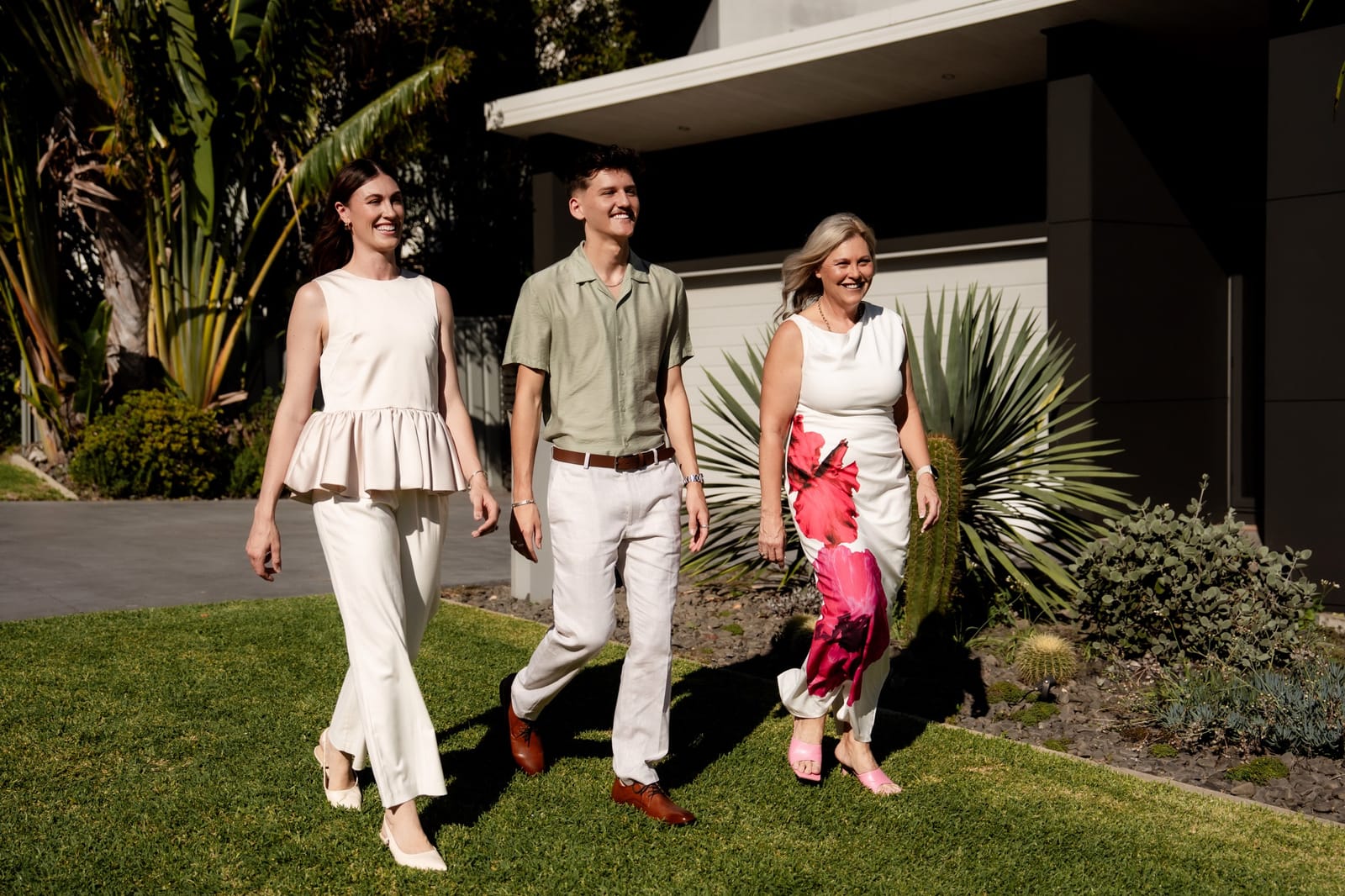 Monique Field, Jordan Thomas and Phoenix Smith walking across the front lawn of a home
